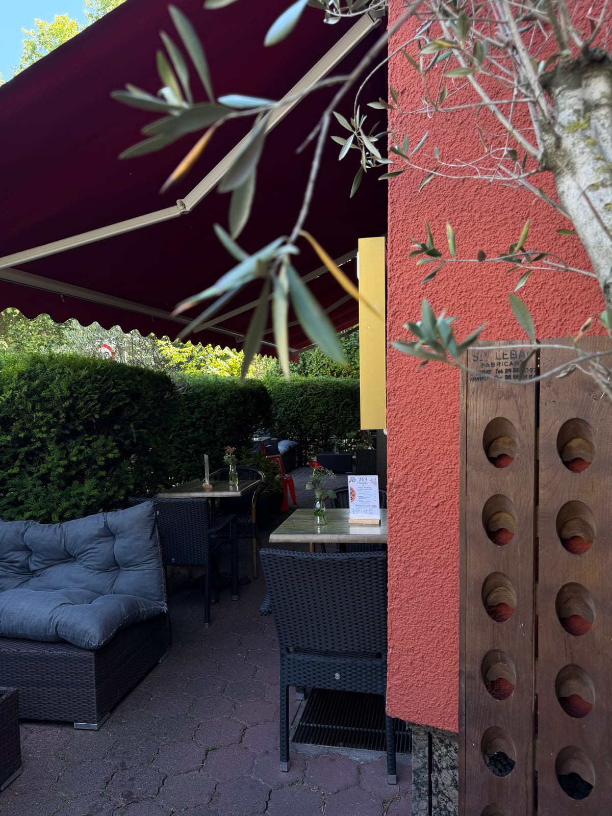 Die Terrasse des 269 mit Sitzplätzen unter der Markise und Olivenzweigen