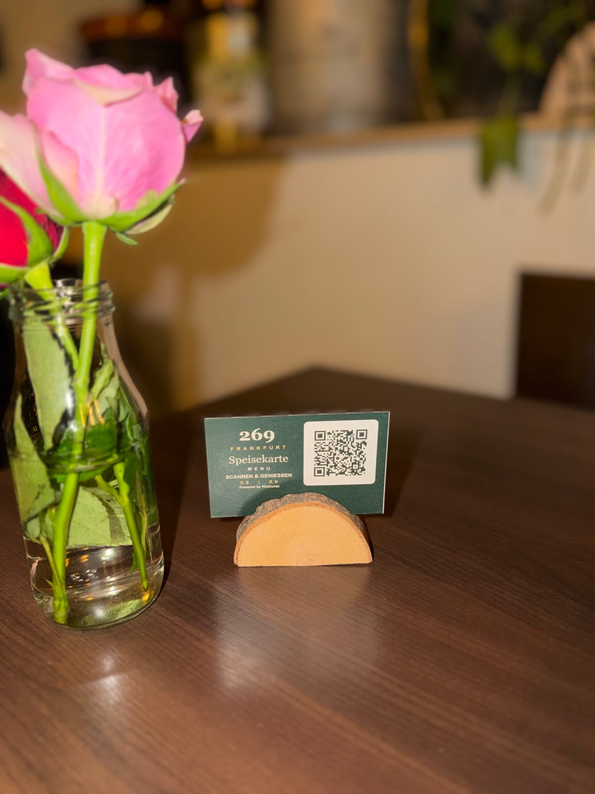 Eine rosa Rose neben dem 269-Speisekartenaufsteller auf einem Holztisch